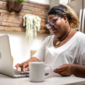 woman working on her laptop at the kitchen table