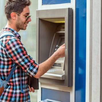 A young man uses an ATM.