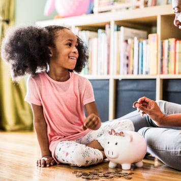Mother and daughter putting money in piggy bank
